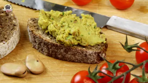 Eine Scheibe Schwarzbrot, die mit Ackerbohnenaufstrich bestrichen ist