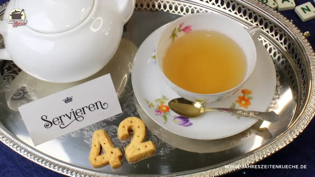 Auf einem silbernen Tablett steht eine Tasse Tee. Daneben liegt Shortbread in den Zahlen 4 + 2