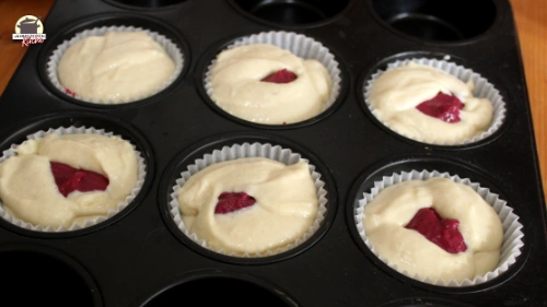 Muffinförmchen gefüllt mit Teig und Bombeer Curd