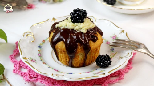 Ein Muffin mit Brombeer Curd-Füllung auf einem kleinen Porzellanteller