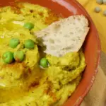 Erbsenhummus in einer Schale mit Olivenöl und Weißbrot angerichtet