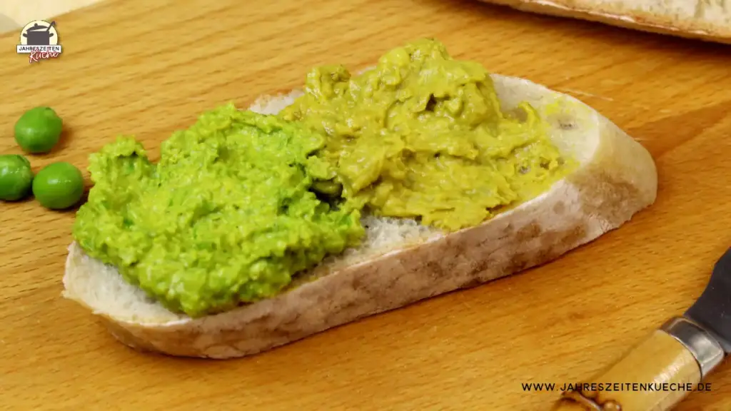 Eine Scheibe Weißbrot ist mit 2 Arten Erbsenhummus bestrichen. Links aus frischen grünen Erbsen, rechts aus getrockneten Erbsen